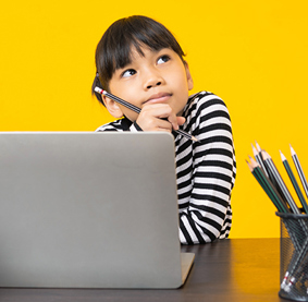 A thoughtful child holding a pencil sits at a desk with a laptop and pencils, against a bright yellow background.